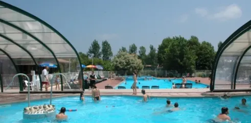 Piscine couverte du Camping Le Col Vert avec des enfants nageant et des adultes se détendant.