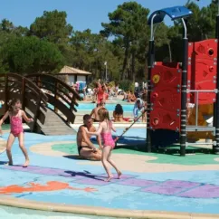 Enfants sur une aire de jeu aquatique avec un adulte, Camping La Côte d'Argent