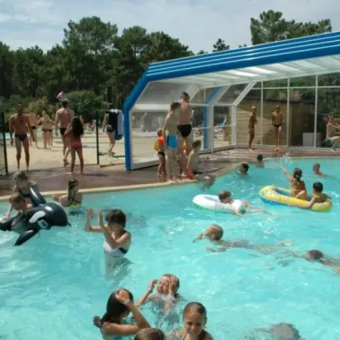 Nageurs dans une piscine couverte avec ballon de football flottant au Camping La Côte d'Argent