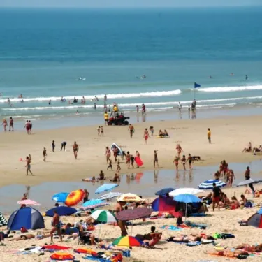 Plage animée avec parasols, tentes et baigneurs au Camping La Côte d'Argent