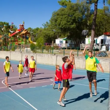 Photo camping La Côte d'Argent : enfants jouent au basket sur un terrain extérieur.