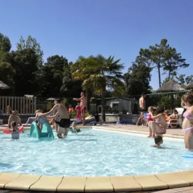 Enfants jouant dans une piscine entourée de parasols à Camping Le California
