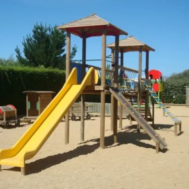 Parc infantile en bois avec toboggan jaune, escaliers et structures pour enfants