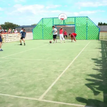 Enfants jouent au basket sur une cour extérieure du Camping Le Chaponnet