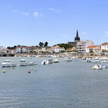 Port animé avec bateaux amarrés et ville en arrière-plan sous un ciel bleu