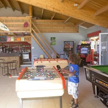 Enfant jouant au football sur table dans le centre de loisirs du Camping Les Cyprès