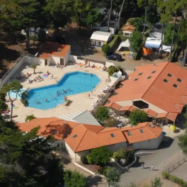 Vue aérienne du camping avec piscine, mobil-homes et forêt environnante