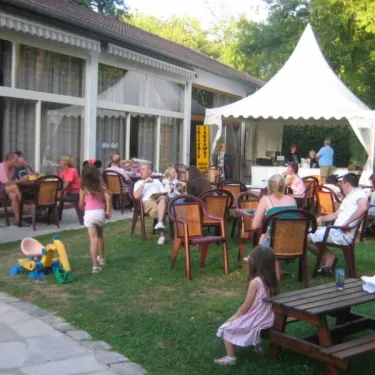 Groupe de personnes autour d'une tente blanche et d’une table en plein air, Camping Etangs Fleuris