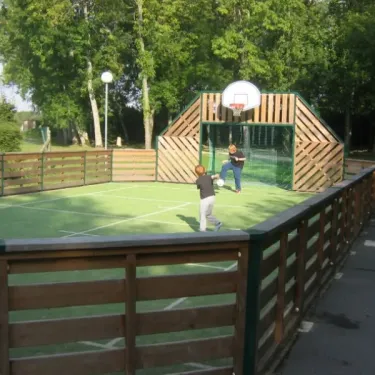 Enfants jouant au basket-ball sur une aire de jeu en herbe au Camping Etangs Fleuris.