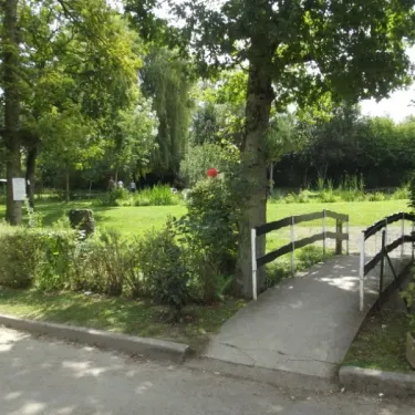 Allée verdoyante avec un pont en bois au Camping Etangs Fleuris