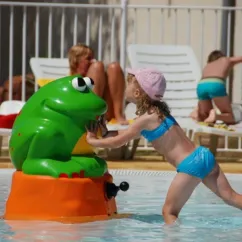 Enfant joue avec une fontaine de grenouille dans la piscine du Camping Cayola
