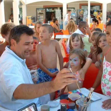 Artiste peignant le visage d'une enfant au Camping Cayola