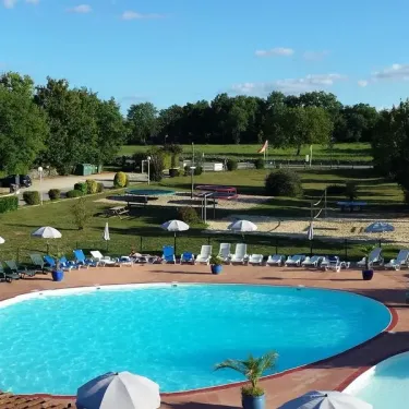 Piscine ovale avec chaises longues et parasols au Camping Les Cigales