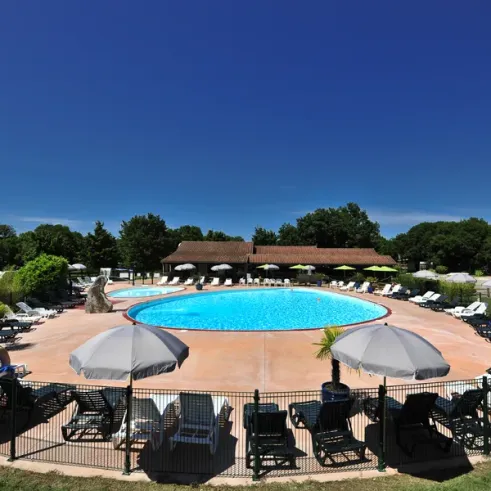 Camping Les Cigales - piscine entourée de transats et parasols sous un ciel bleu