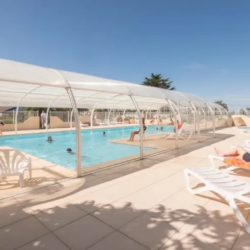 Piscine couverte avec chaises longues et visiteurs au Camping Ker Vella