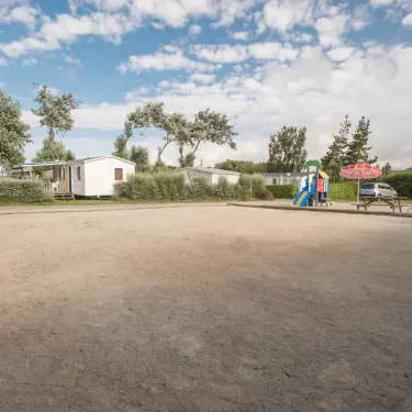 Photo camping Ker Vella : espace de jeux avec toboggan et mobile homes.