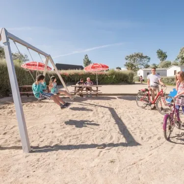 Enfants jouent sur un parc de jeux en bois au Camping Ker Vella