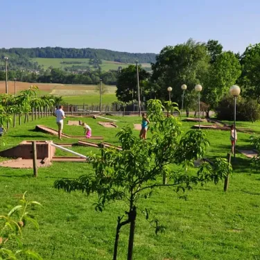Mini-golf au Camping Du Bois de Reveuge avec enfants en plein jeu sur un parcours verdoyant.
