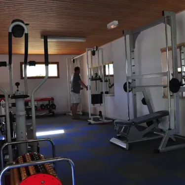 Salle de fitness du Camping Du Bois de Reveuge avec équipements de musculation.