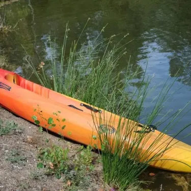 Canot orange à côté d'un lac avec des roseaux, Camping Grand Sud