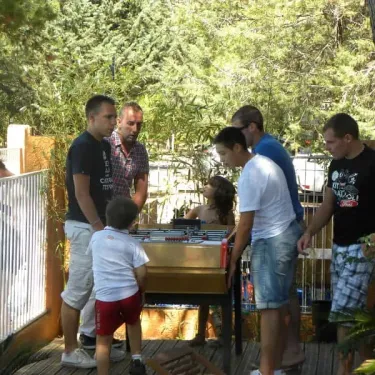 Quatre hommes et un enfant jouent au football sur table à Camping Val Roma Park.