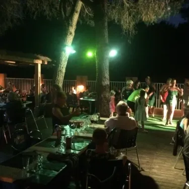 Camping Val Roma Park : soirée nocturne en extérieur avec danse et convivialité sous les arbres.