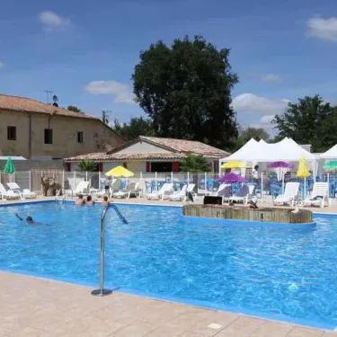 Piscine extérieure entourée de chaises longues et de parasols, Camping Des Etangs.