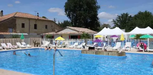 Piscine extérieure entourée de chaises longues et de parasols, Camping Des Etangs.
