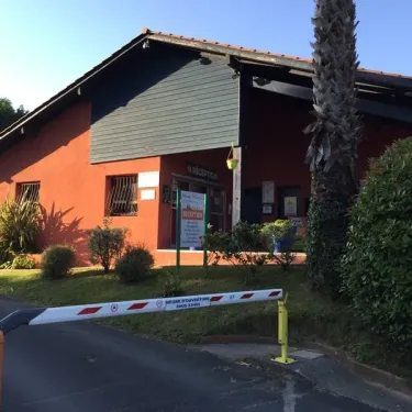Photo Camping Bela Basque avec bâtiment d'entrée et barrière de sécurité.