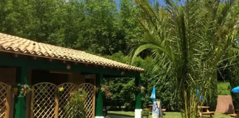 Camping La Bernede avec maison verte et palmier sous un ciel bleu.