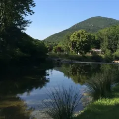 Lac calme entouré de forêt et de collines vertes près du Camping La Bernede.