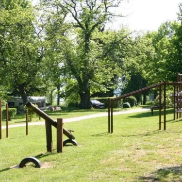 Parc d'activités extérieur avec équipements pour enfants au Camping Le Manoir de Bezolle
