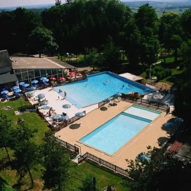 Piscine avec parasols et visiteurs au Camping Le Manoir de Bezolle