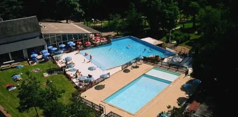 Piscine avec parasols et visiteurs au Camping Le Manoir de Bezolle