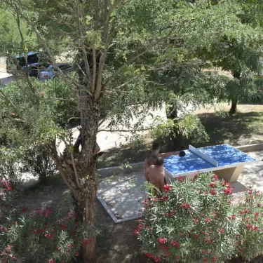 Photo Camping Aloha Plage avec table de ping-pong et personnes jouant en plein air.