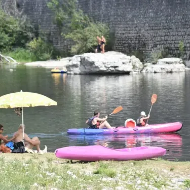 Personnes en kayak sur un lac avec parasol jaune à la rive