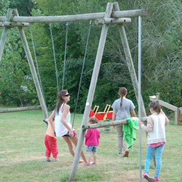 Enfants jouant sur une aire de jeux avec des balançoires au Camping de Bergougne.
