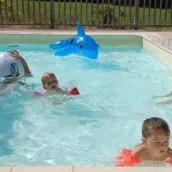 Enfants jouent dans la piscine avec un dauphin gonflable, Camping De Bergougne