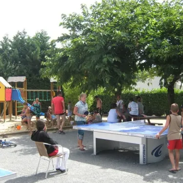 Enfants jouent au ping-pong dans le parc du Camping Le Chant des Oiseaux