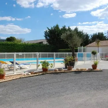 Piscine avec chaises longues et clôture au Camping Le Chant des Oiseaux
