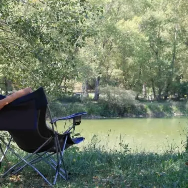 Chaise pliante sur l'herbe près d'un lac dans le camping La Rivière