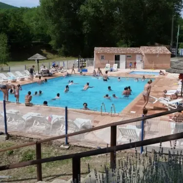 Piscine du Camping La Rivière avec personnes nageant et chaises longues