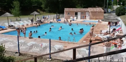 Piscine du Camping La Rivière avec personnes nageant et chaises longues