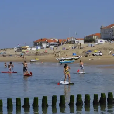 Personnes pratiquant le paddle surf sur la plage du Camping Des Pins