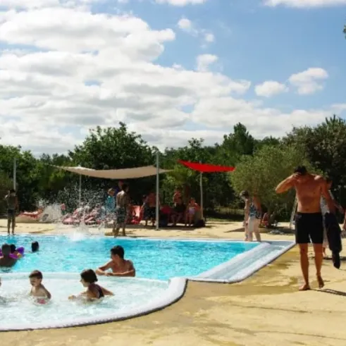 Camping Des Pins : enfants dans la piscine, adultes autour, ciel bleu nuageux