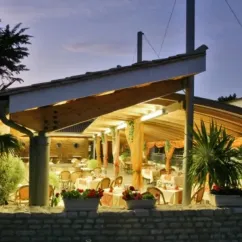 Terrasse extérieure éclairée avec tables et chaises au Camping Les Grenettes