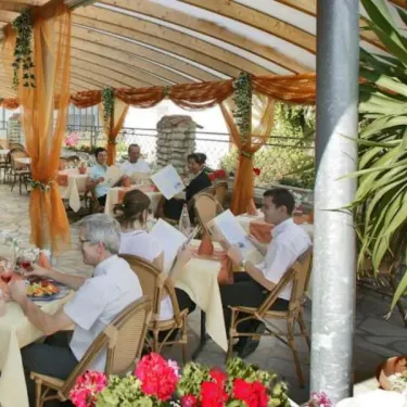 Terrasse extérieure du restaurant du camping Les Grenettes avec des convives.
