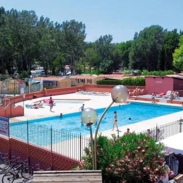 Piscine entourée d'arbres avec vélos au Camping le Sourire