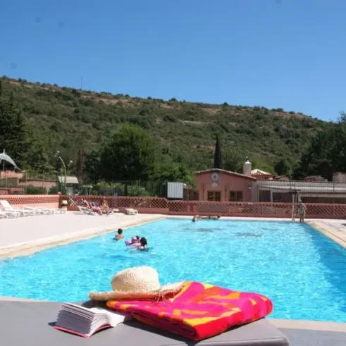 Piscine avec chaise longue et livre au Camping le Sourire