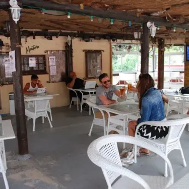 Camping le Sourire : terrasse avec tables blanches et clients.
